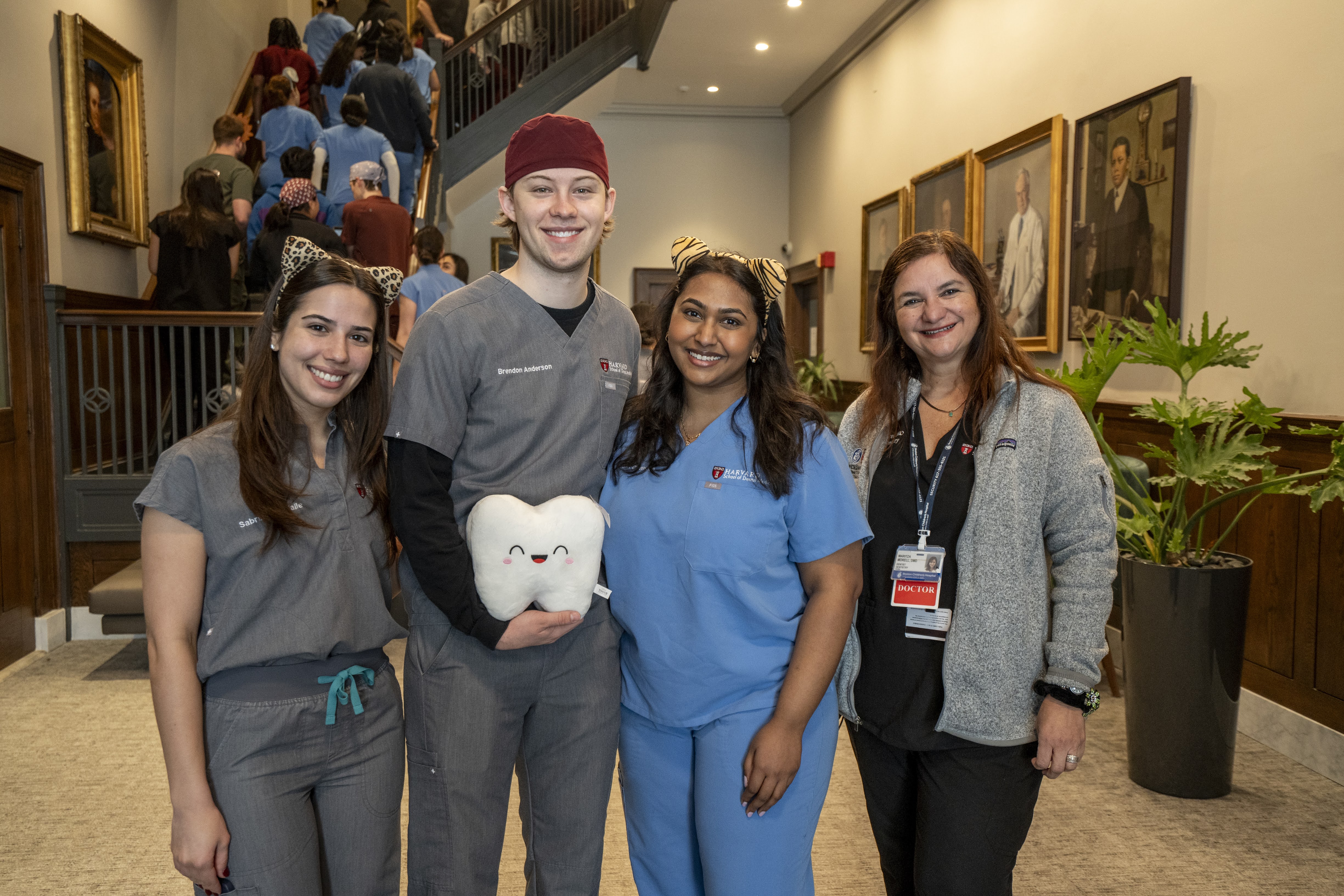 Dental students in scrubs one holding a stuffed tooth