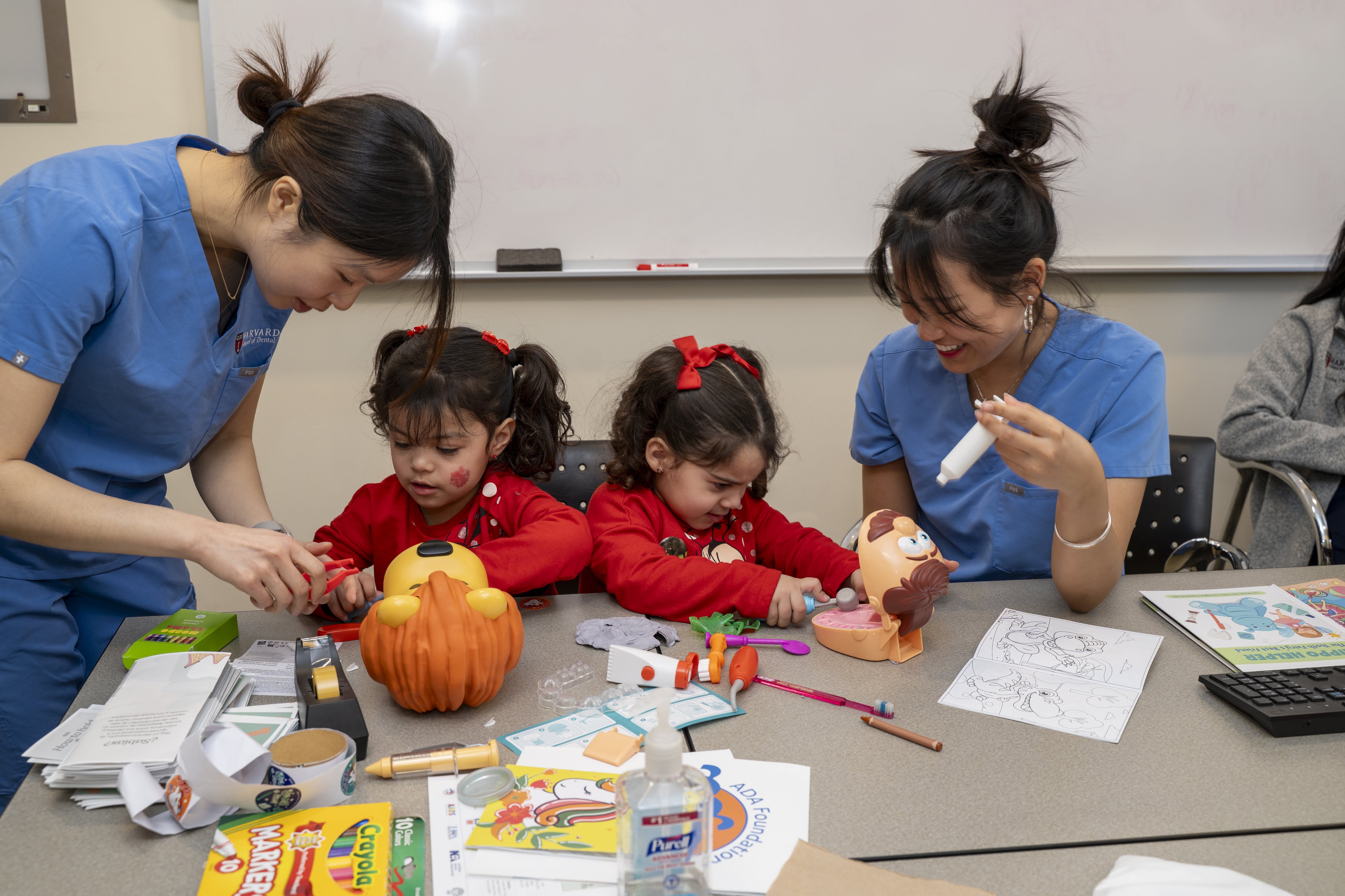 two students helping two children with crafts