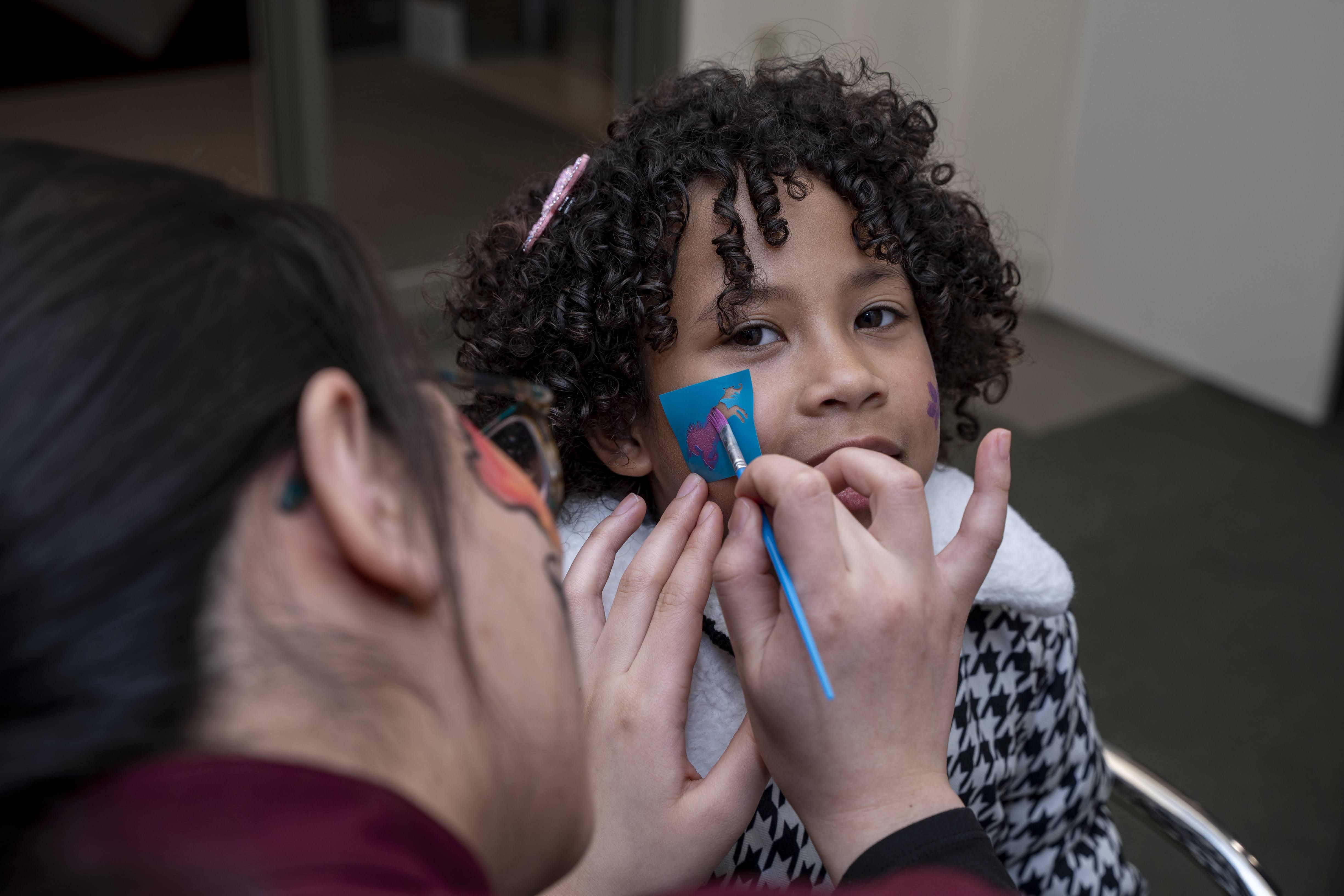 Student using a stencil to paint on a child's cheek