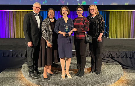 Four colleagues from Harvard School of Dental Medicine posing together, with Dr. Sang Park (center) holding her award.