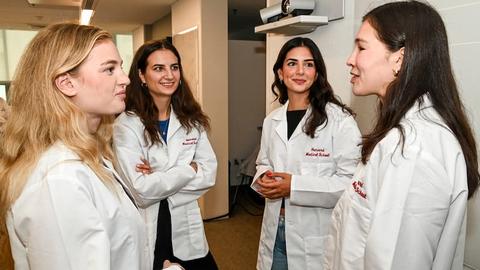 A group of femaie students in white coats standing and talking