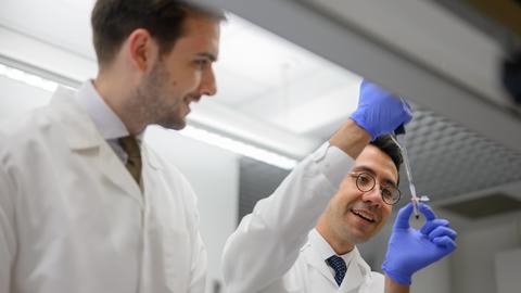 Two people working with syringes in a lab