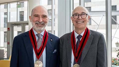 Drs. Maurizio Tonetti and Stephen Sonis wearing their Distinguished Alumni Award medals standing in the REB lobby