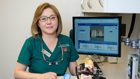 Dr Nagai in from for a computer screen holding a mouth model