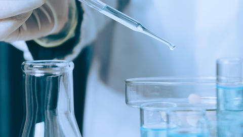 Researcher with glass laboratory chemical test tubes with liquid.