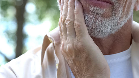 close up of a bearded man with a hand on the side of his face