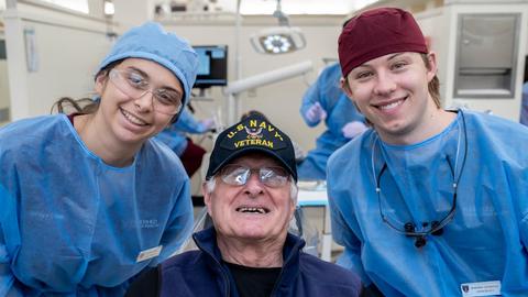 Students with a veteran sitting in a dental chair
