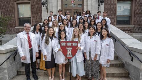 class of dental students in white coats on steps