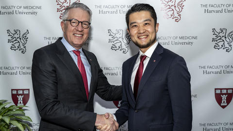 Two people shaking hands and smiling at camera