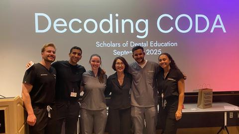 students next to a lecturn in front of a screen
