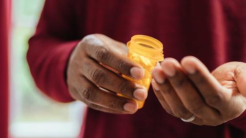 cropped image of a person holding a presciption vial with pills and the other hand is opened