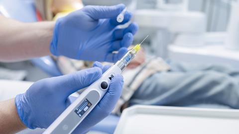 a gloved hand holding endodontic device in a modern dental clinic