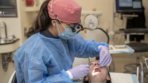 clinician in PPE examining a patients mouth