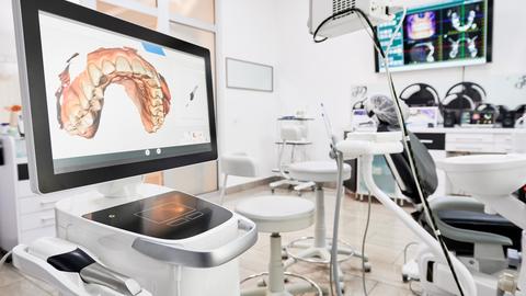 Interior of dental office with modern equipment and dental intraoral scanner with teeth on display, medical system for intraoral scanning.