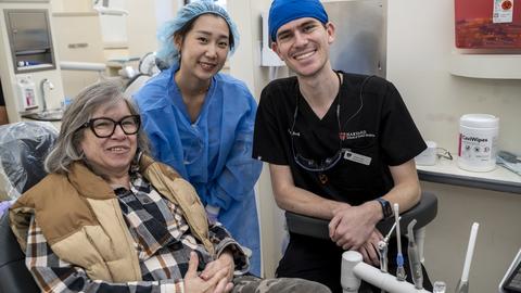 Vet sitting in dental chair with two dental students