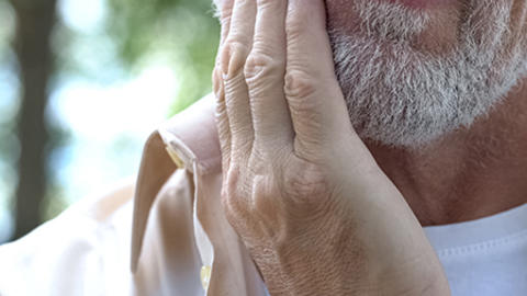 A man holding his hand up to his jaw.