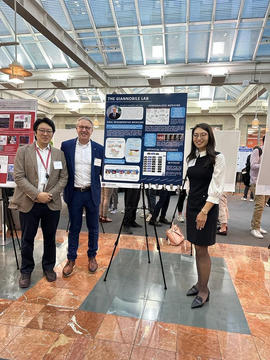 Three people standing by a poster
