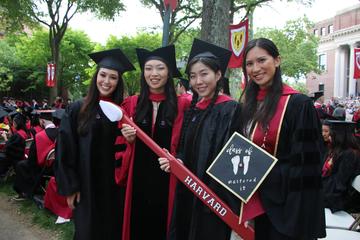 Four graduates holding a large red toothbrush