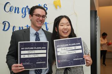 Two students holding signs that show off where they matched