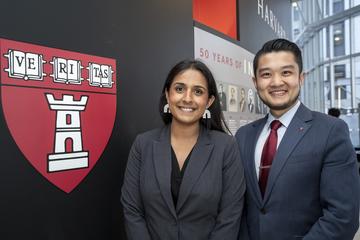 Two people standing next to HSDM logo on wall