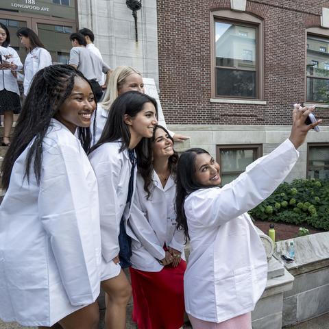 Students wearing white coats taking a selfie