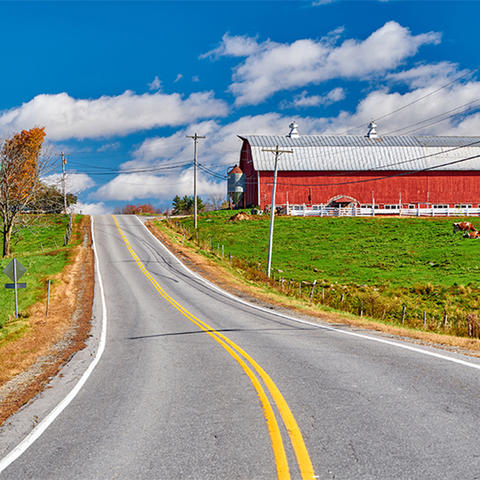 country two lane road with a red barn in the distance