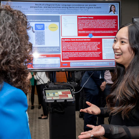 Student in front of a monitor speaking to a female who has back turned to camera