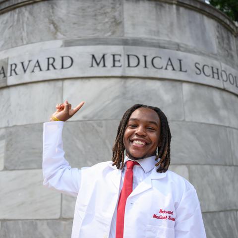 student pointing to medical school name at the entrance of the Quad