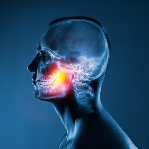 X-ray of a man's head on blue background. Jaw joint is highlighted by yellow red color