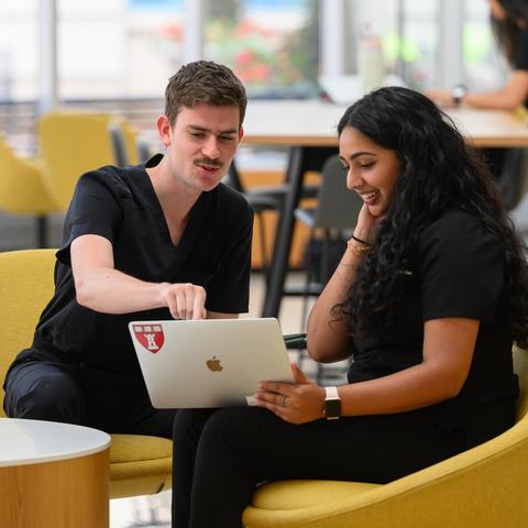 two students in the REB lobby looking at laptop