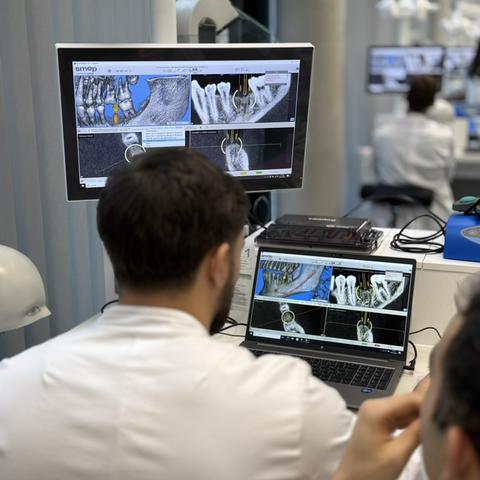 Back of a dentist looking at a screen