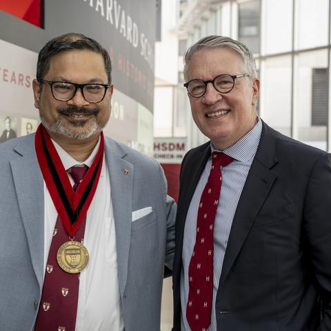 Shahid Aziz wearing his medal standing next to the dean,