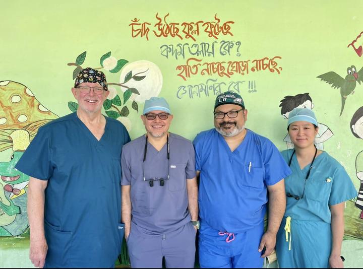 Four people wearing scrubs standing in front of a colorful wall