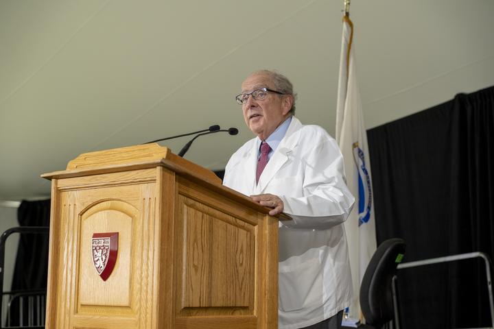 Dean Bruce Donoff speaking at podium in a white coat