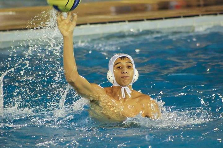 Boy in a pool raising hand to a ball