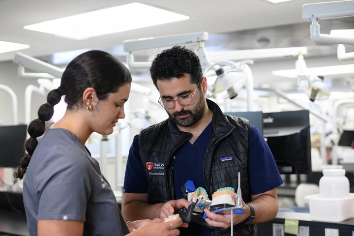 Instructor reviews dental models with a student in a clinical teaching space at Harvard School of Dental Medicine.