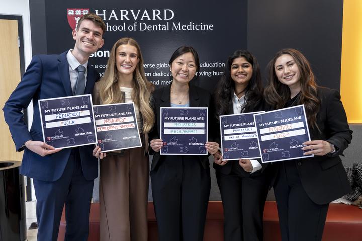 5 students holding their match day signs, smiling for the camera