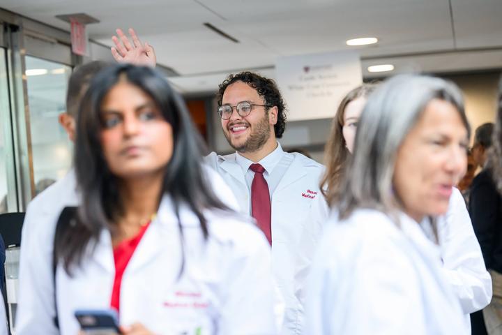 Student in white coat waving