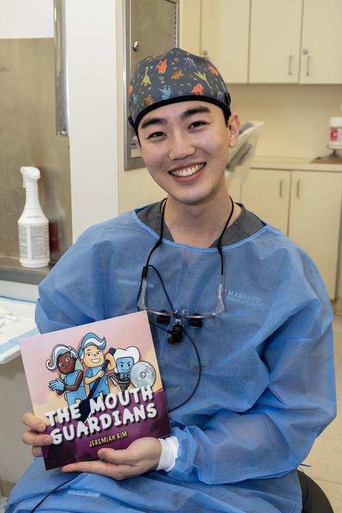 Student wearing scrubs holding book 