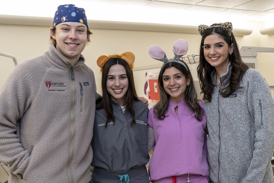 Four students wearing scrubs smiling and standing in a clinic
