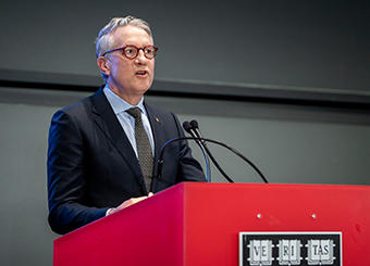 HSDM's Dean William Giannobile standing at a podium with Harvard Veritas seal. 