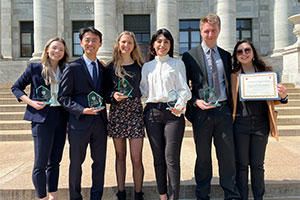 Program founders stand in front of the medical school displaying their awards.