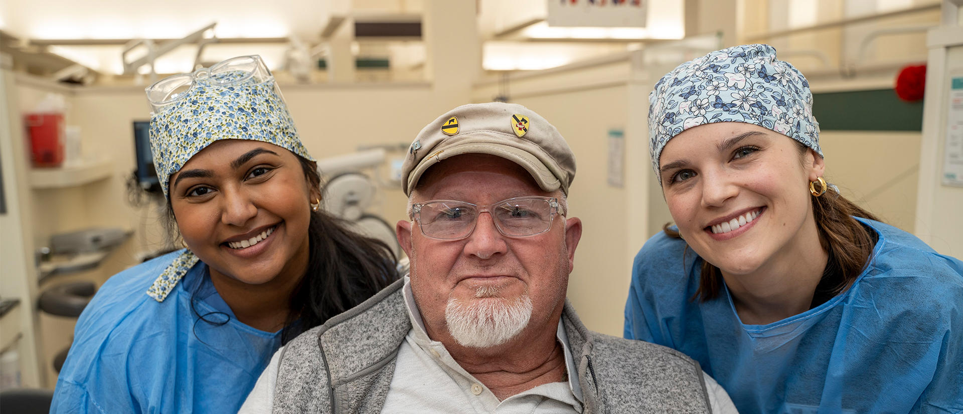 Two female students flank a vet in a dental chair