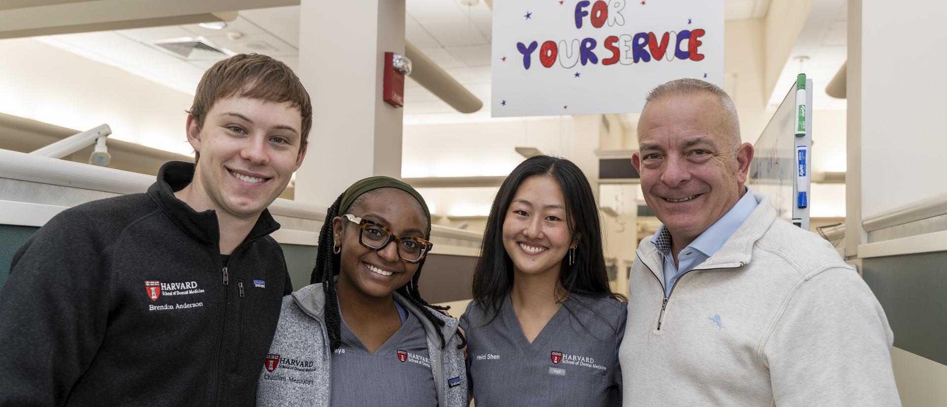 Tom Miller with dental students standing under a sign that says Thank you veterans