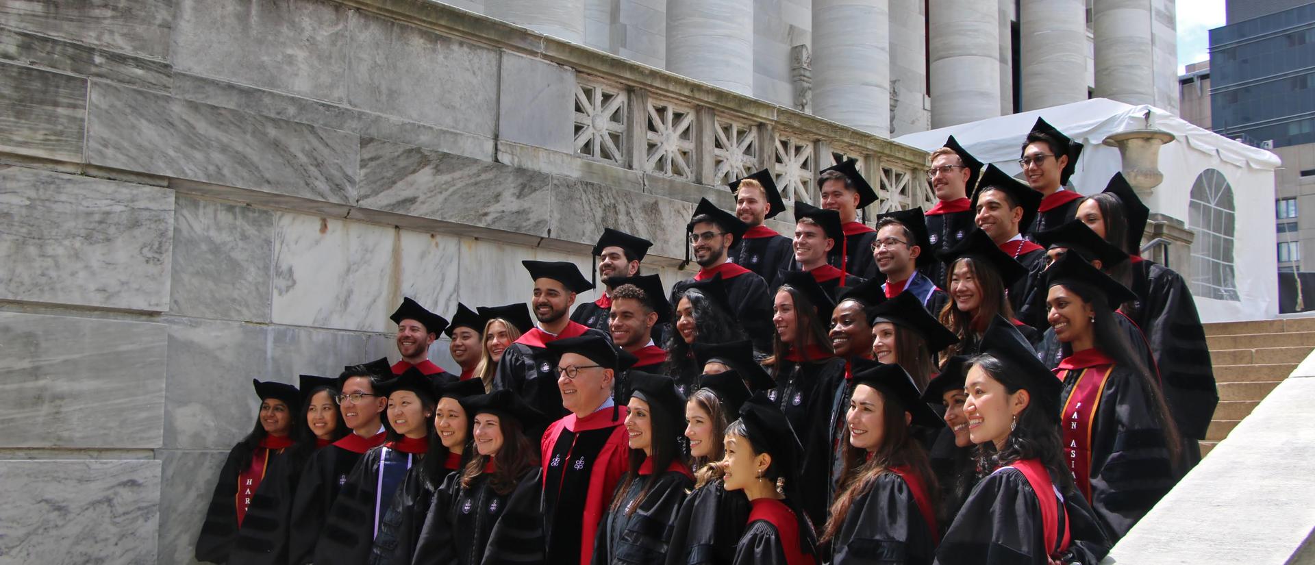 students in cap in gown on the steps in front of Gordon Hall