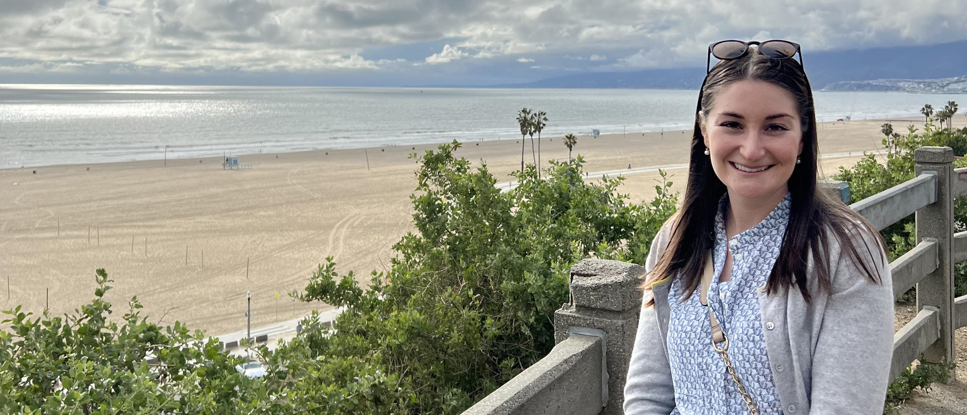 Abigail stands on boardwalk in front of ocean