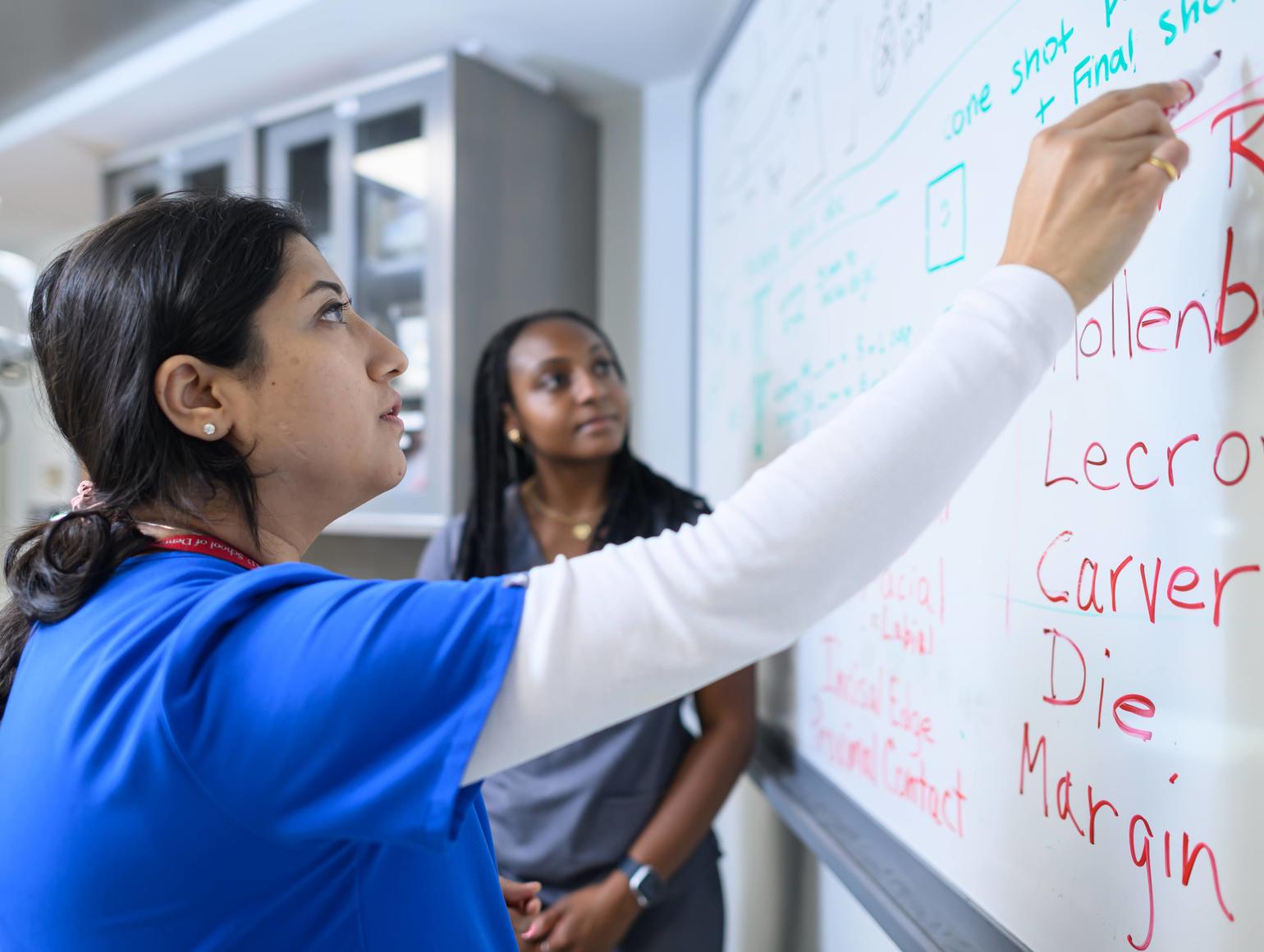 faculty member writing on a whiteboard