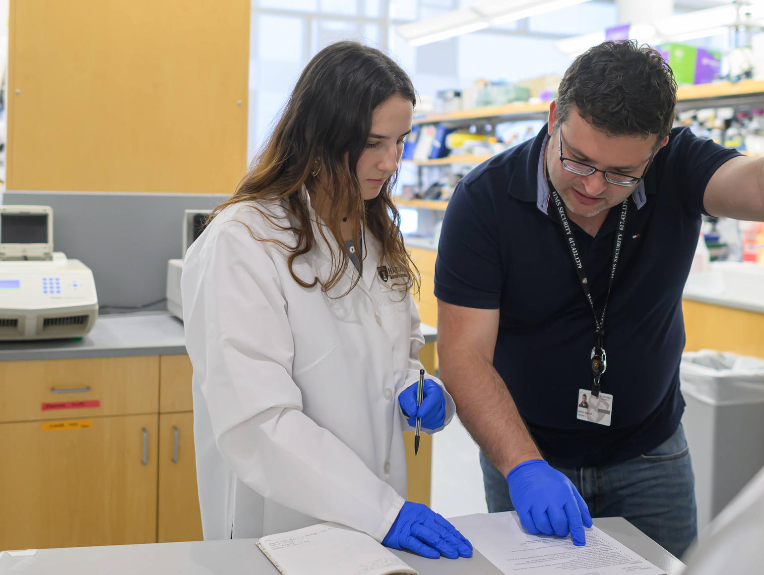 Student and instructor in lab reading notes 