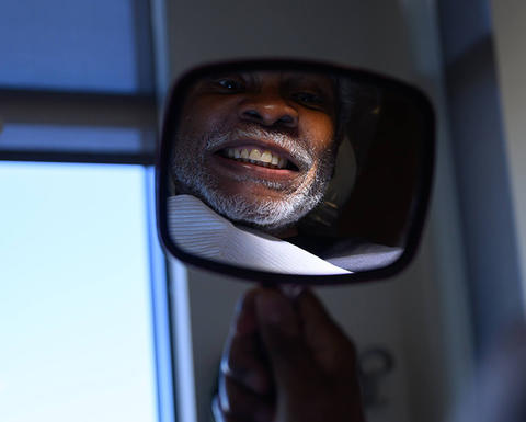 patient looking at teeth in handheld mirror