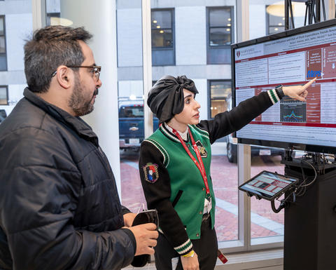 Candidate explains a research poster to an attendee.